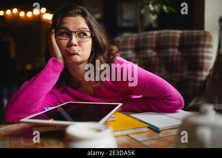 Portrait d'une jeune femme travaillant dans une maison de café tout en se penchant face à portée de main et grimace Banque D'Images