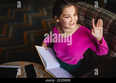 Vue de dessus du menu et de l'apparence de Happy Pretty female par la fenêtre tout en agitant à la main Banque D'Images