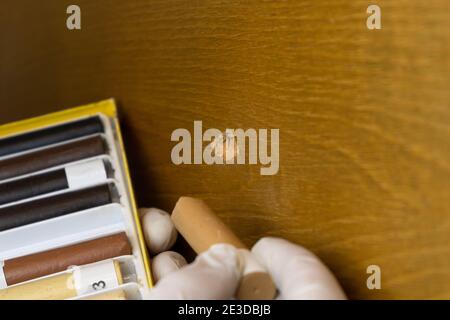 restauration de meubles, le maître ferme le trou dans la surface en bois avec des crayons de cire en gros plan Banque D'Images