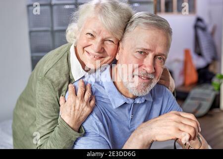 couple âgé des années 60 se détendant à la maison, posant regardant l'appareil photo souriant moment de prise de vue pour la photo d'album de famille en intérieur, grands-parents aux cheveux gris Banque D'Images