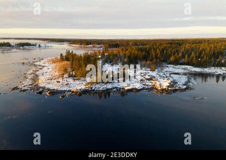 Vue panoramique aérienne du coucher de soleil d'hiver panoramique réflexions de la mer Iced à la petite péninsule rocailleuse de Kont, Umea, Suède. Hiver arbre de pin scandinave pour Banque D'Images