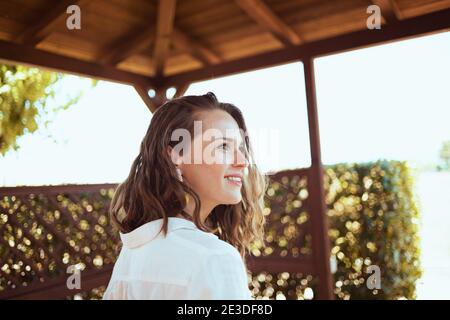 femme de ménage souriante, élégante et d'âge moyen, chemise blanche dans le patio. Banque D'Images