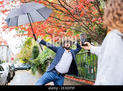 Jeune couple avec smartphone pour la vidéo des médias sociaux en plein air dans la rue. Banque D'Images