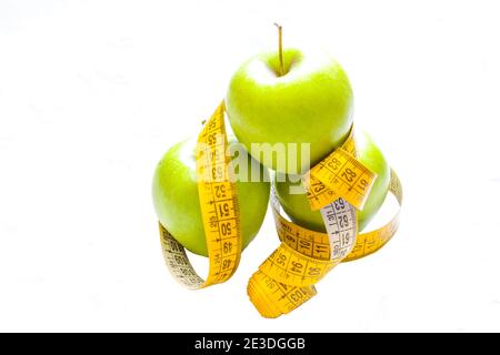 Régime alcalin. Pommes vertes gros plan avec mètre-ruban isolé sur fond blanc. Alimentation mince et manger pour la santé. Banque D'Images
