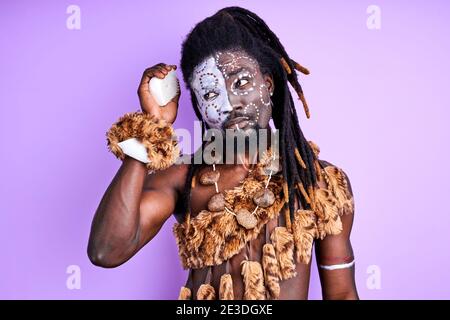 aborigen homme essayer d'utiliser peigne pour la première fois de manière correcte, il est malentendu. isolé fond violet Banque D'Images