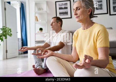 Calme calme serein vieux de l'âge moyen 50s couple méditant à la maison. Banque D'Images
