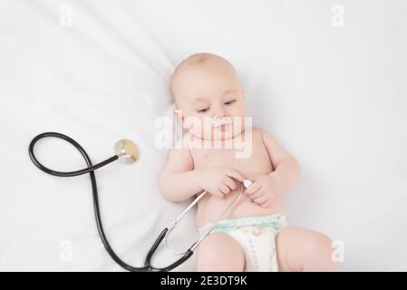 Bébé doux avec stéthoscope sur fond blanc Banque D'Images