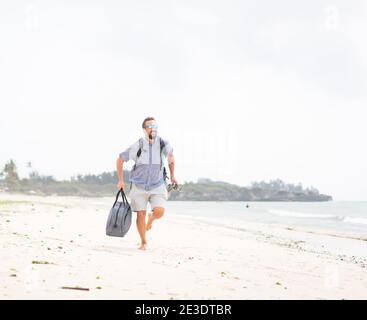 Homme adulte gai avec sac de plaisir sur le tropical plage Banque D'Images