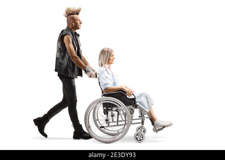 Punk homme poussant une jeune femme patiente dans un fauteuil roulant isolé sur fond blanc Banque D'Images