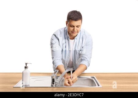 Jeune homme décontracté se lavant les mains dans un lavabo isolé arrière-plan blanc Banque D'Images