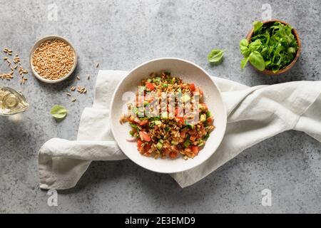 Savoureuse salade maison de céréales à grains entiers épeautre avec légumes frais sur table grise. Vue de dessus. Banque D'Images