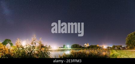 Panorama de l'évaporation sur le lac de la rivière près de Maisons dans le village. Ciel étoilé de nuit au-dessus de la rivière Lake avec étoiles brillantes et piste météorique. Brillant Banque D'Images