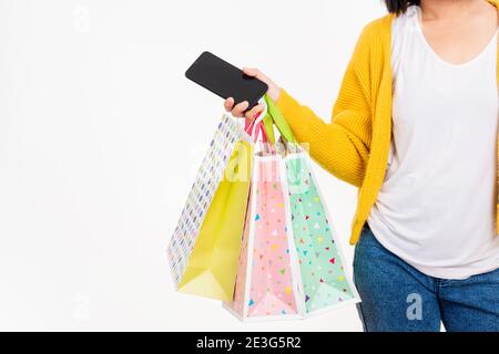 Bonne jeune femme tient beaucoup de paquets dans les bras et en utilisant le téléphone portable intelligent pour faire des achats en ligne, la main tenant des sacs de shopping multicolore isoler Banque D'Images