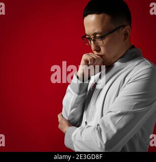 Portrait d'un jeune homme sérieux et réfléchi médecin urologue ou proctologue en robe médicale blanche tenant la main sur son visage Banque D'Images