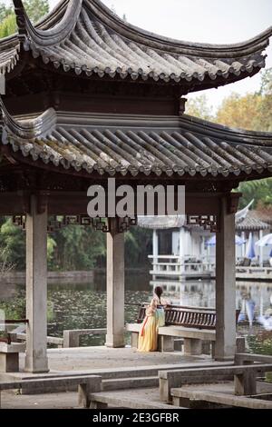 Huzhou, Chine, 18 novembre 2020: Femme chinoise portant une robe traditionnelle et tenant un fan dans le parc en Chine. Happy Spring Festival, nouvel an chinois Banque D'Images