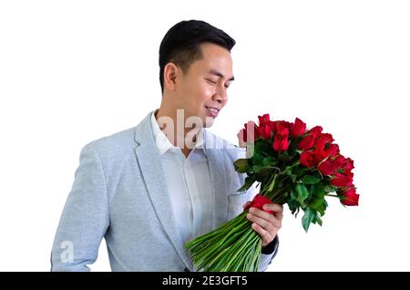 Homme asiatique portant un costume gris tenant un bouquet de roses rouges isolé sur fond blanc pour anniversaire ou le concept de la Saint-Valentin. Banque D'Images