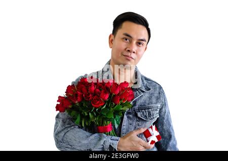 Homme asiatique portant une veste de Jean portant un bouquet de rouge roses et boîte cadeau rouge isolée dans fond blanc pour Concept anniversaire ou Saint-Valentin Banque D'Images