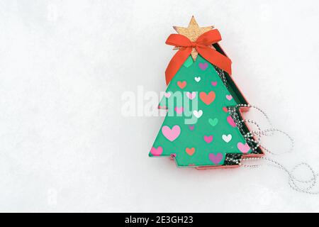 Boîte cadeau sous forme d'arbre de Noël. Et guirlande de Noël dans la neige il y a un endroit pour le texte. Concept Noël, nouvel an. Photo de haute qualité Banque D'Images