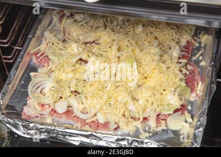 Faire cuire au four des morceaux de viande assaisonnés de fromage râpé sur une plaque de cuisson. Concept de cuisine, cuisine,. Photo de haute qualité Banque D'Images