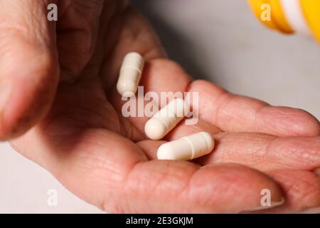 Une femme âgée verse des pilules d'un pot dans sa main. Concept de santé des personnes âgées. Soins infirmiers et soins aux parents âgés. Mise au point sélective. Banque D'Images