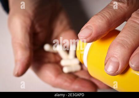 Une femme âgée verse des pilules d'un pot dans sa main. Concept de santé des personnes âgées. Soins infirmiers et soins aux parents âgés. Mise au point sélective. Banque D'Images