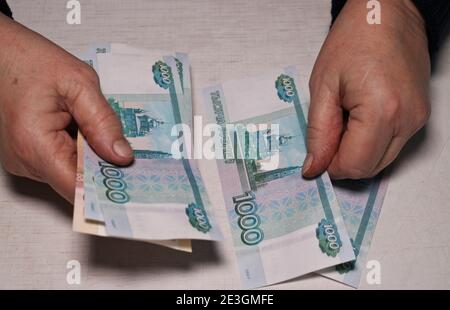 Une femme âgée compte des billets de mille roubles. Les mains et l'argent de la vieille femme. Vieillesse, épargne-retraite et concept d'investissement. Banque D'Images