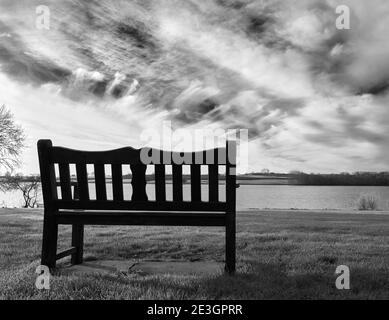 Banc en bois solitaire et inoccupé sur la rive d'un lac, le matin d'hiver ensoleillé Banque D'Images