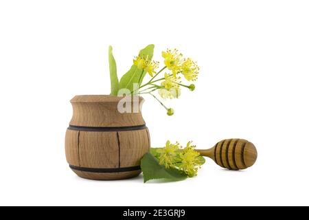 Petit pot en bois de fleurs et de feuilles de tilleul jaune fraîchement cueillies, également appelé tilia et baguette en bois sur fond blanc Banque D'Images