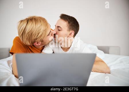 Couple gay aimant embrassant et utilisant l'ordinateur portable à la maison Banque D'Images