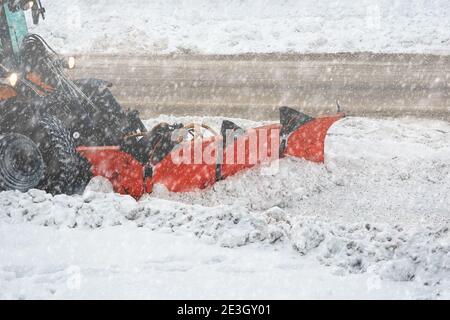 Déneigement avec chasse-neige articulé de la rue urbaine en hiver. Banque D'Images