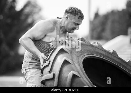 Un jeune homme lève une grosse roue lourde en compétition Banque D'Images