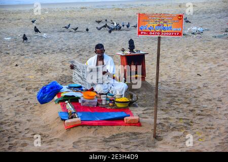 Hindu Priest lisant le journal, avant de laver les péchés des pèlerins, Varkala Beach, Varkala, Kerala, Inde Banque D'Images