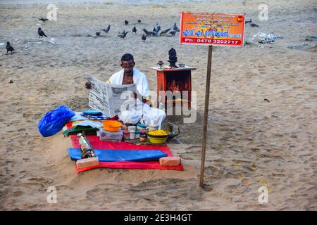 Hindu Priest lisant le journal, avant de laver les péchés des pèlerins, Varkala Beach, Varkala, Kerala, Inde Banque D'Images