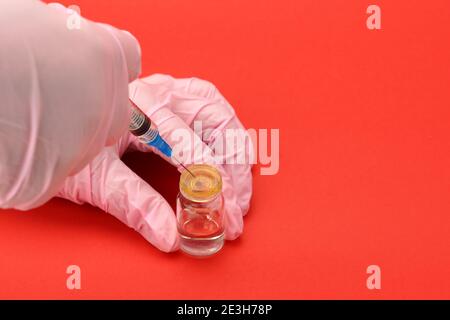 Un travailleur médical portant des gants tient une seringue jetable et un flacon d'un médicament ou d'un vaccin. Banque D'Images