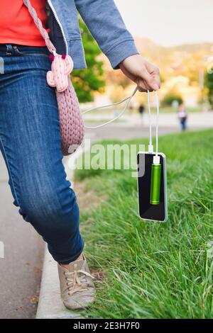 Une fille tient par câble un smartphone et une banque d'alimentation externe pendant la charge. Banque D'Images