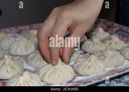 Boulettes géorgiennes à la viande. La main tient le khinkali par la queue. Banque D'Images