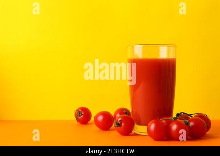 Verre de jus de tomate et tomates sur fond jaune Banque D'Images