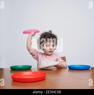 Un tout-petit joue avec des plats en plastique à une table Banque D'Images