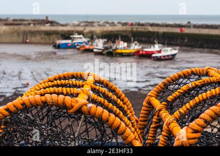 Vue sur les bateaux du port de Staithes, dans le North Yorkshire, au Royaume-Uni, avec des pots de homard au premier plan Banque D'Images