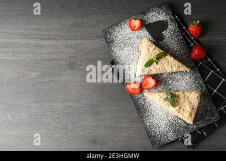 Planche avec des morceaux de gâteau Napoléon avec fraise sur noir arrière-plan Banque D'Images