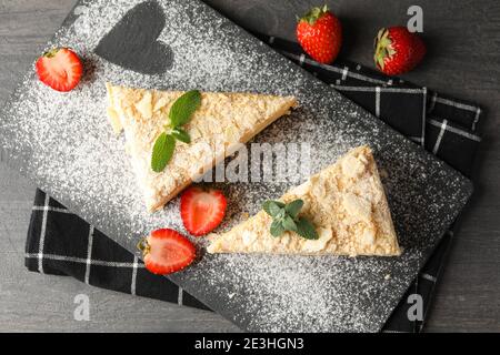 Planche avec des morceaux de gâteau Napoléon avec fraise sur noir arrière-plan Banque D'Images