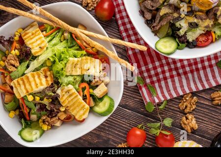 salade de halloumi et salade de bœuf dans deux assiettes séparées sur fond de bois. Banque D'Images