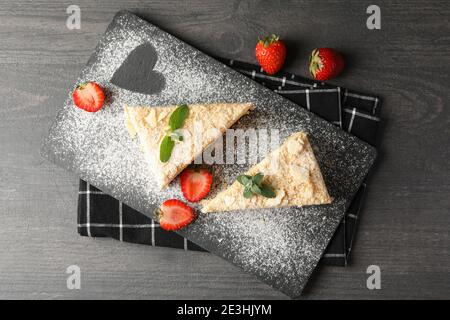 Planche avec des morceaux de gâteau Napoléon avec fraise sur noir arrière-plan Banque D'Images