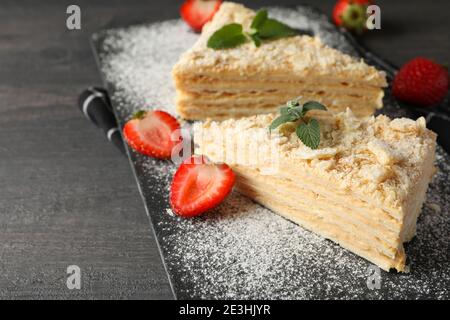 Planche avec des morceaux de gâteau Napoléon avec fraise sur noir arrière-plan Banque D'Images