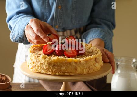 Femme met des fraises sur un délicieux gâteau Napoléon Banque D'Images