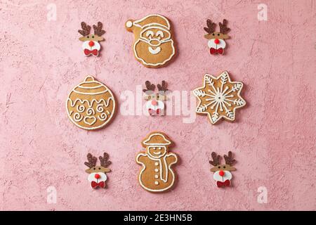 Flat lay de biscuits de gingembre glacés sur rose, biscuits de gingembre de Noël en forme de Père Noël, bonhomme de neige et ornements Banque D'Images