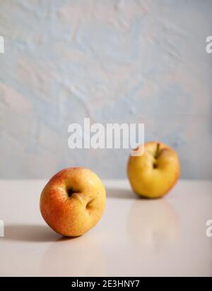 Deux pommes mûres laid reposent sur un fond clair. Verticale. Concept de minimalisme. Une alimentation saine Banque D'Images