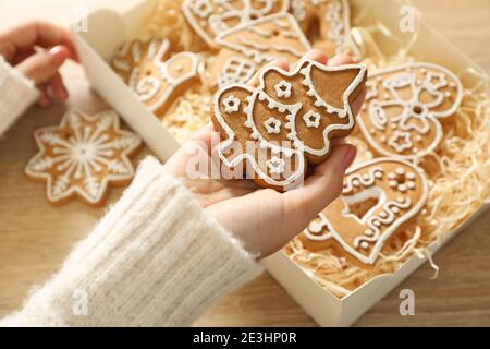 Main d'une femme prenant un biscuit de gingembre glacé d'une boîte de biscuits de gingembre de Noël sous une lumière chaude Banque D'Images
