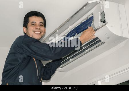 Les réparateurs de climatisation en uniforme bleu vérifient et réparent l'air suspendu au mur. Banque D'Images