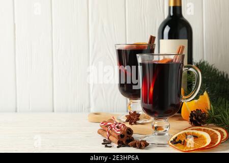 Bouteille de vin et tasses de vin chaud épicé sur bois, ingrédients pour le vin chaud dans une scène hivernale rustique Banque D'Images
